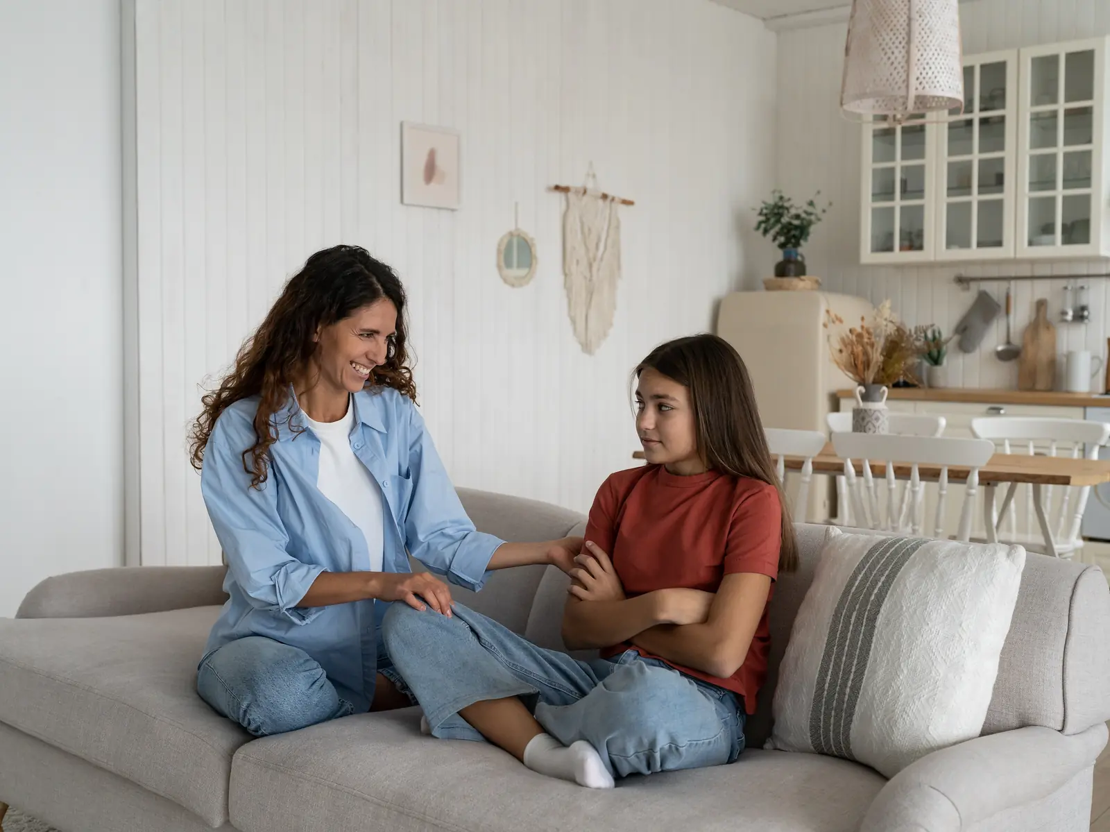 Madre hablando con su hija adolescente en el sofá sin gritos, taller para padres de adolescentes