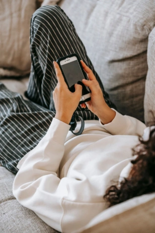 Mujer eligiendo un curso online de Crece con Amor desde su móvil en el sofá