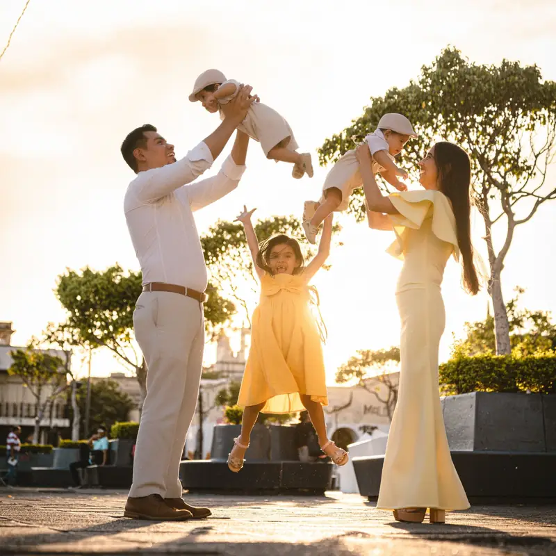 Familia jugando con sus tres hijos en una plaza al atardecer