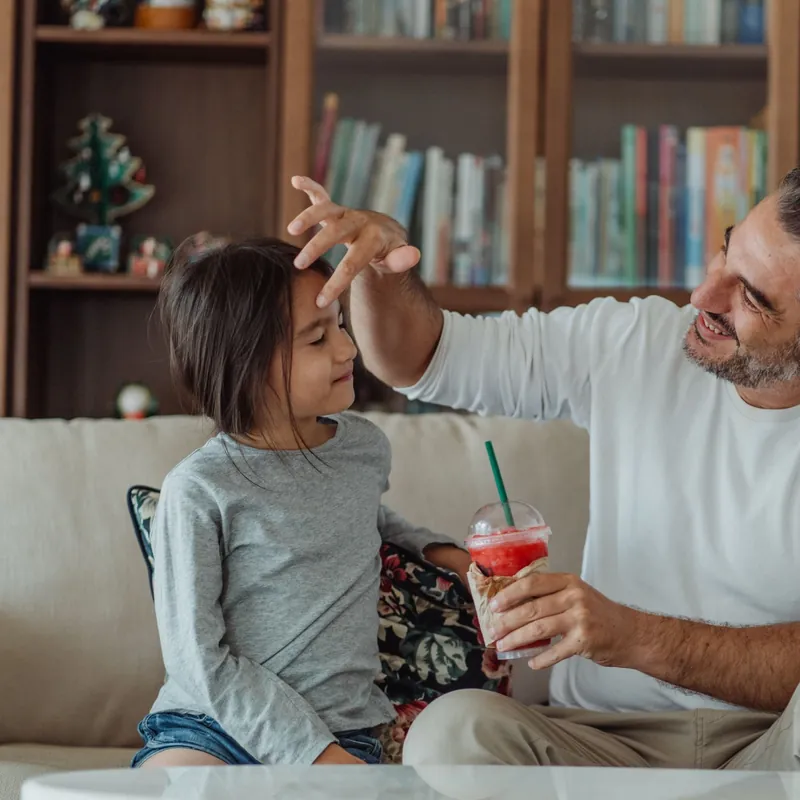 Padre hablando con calma con su hija en el sofá de casa, educar sin gritar