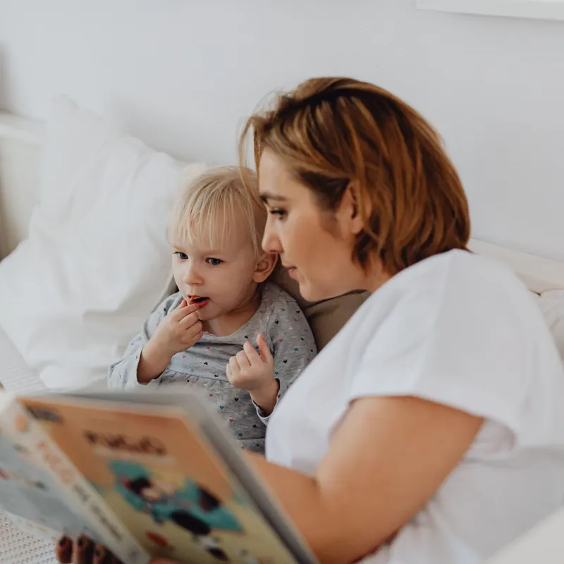 Madre leyendo un cuento a solas con su hija pequeña, tiempo exclusivo para gestionar los celos entre hermanos
